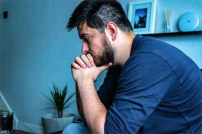 Side view of man sitting at home