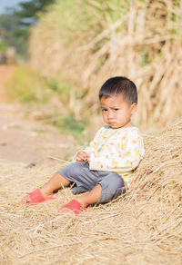 Cute boy looking away while sitting on land