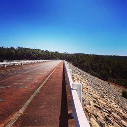 Empty road against clear blue sky