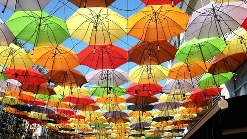 Low angle view of multi colored umbrellas hanging against sky