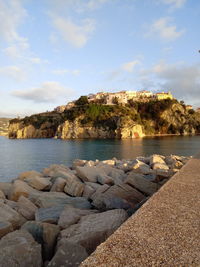 Rocks on shore by sea against sky