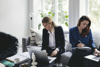 Female coworkers working on sofa at home office