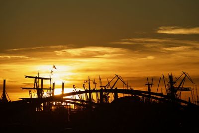 Silhouette cranes against sky during sunset