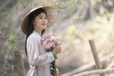 Young woman looking away while holding flowers