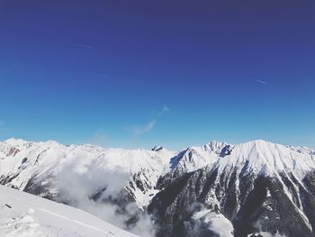 Scenic view of snow mountains against blue sky