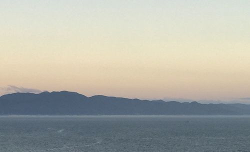 Scenic view of sea and mountains against clear sky