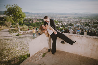 High angle view of playful couple at observation point against cityscape