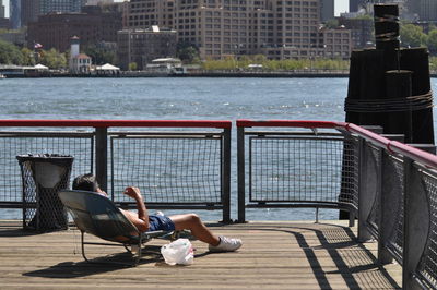Shirtless man sunbathing on promenade by lake