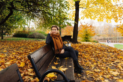 Short-haired blonde rests in an autumn park sitting on a bench