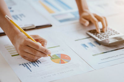 Cropped hands of woman analyzing graphs on office desk