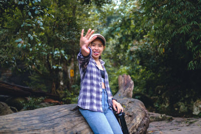 Portrait of young woman standing against trees