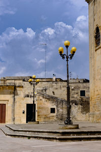 Low angle view of street light by building against sky