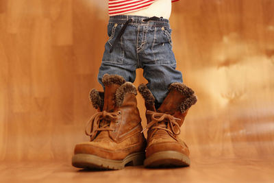 Low section of girl wearing boot on floor