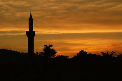 Silhouette tower against orange sky