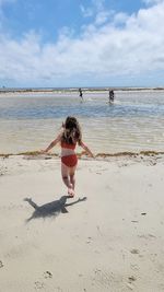 Full length of girl standing at beach against sky