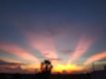 Defocused image of silhouette field against sky during sunset