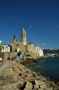 Historic building by sea against blue sky