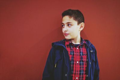 Cute boy standing against red background