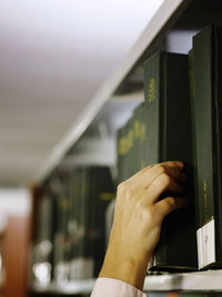 Close-up of human hand removing book from shelf