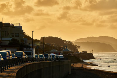 Boats moored at harbor against sky during sunrise