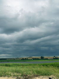 Scenic view of field against storm clouds