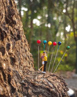 Girl holding balloons on tree trunk