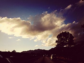 View of country road against cloudy sky
