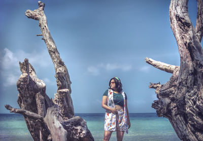 Woman standing by tree against sky