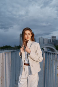 Portrait of young woman standing against railing
