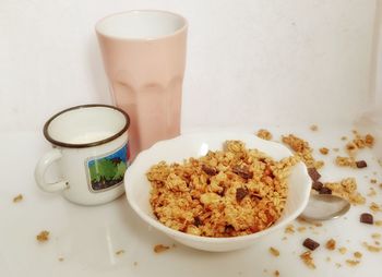 High angle view of muesli served in bowl with milk cup and glass on table