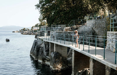 Young woman standing on walkway on rocky coast. summer, tourism, travel.