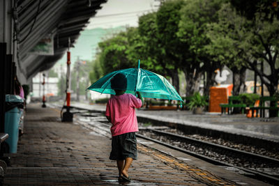 Rear view of woman walking on wet railroad track