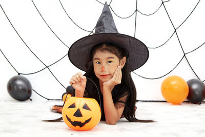 Portrait of boy with pumpkins against pumpkin during halloween