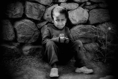 Portrait of boy sitting against wall