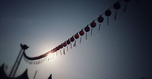 Low angle view of lanterns hanging against clear sky on sunny day