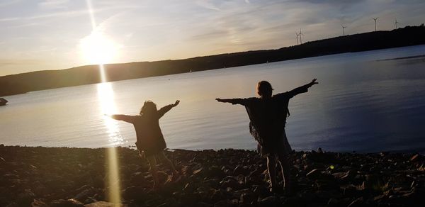 Friends standing on land against sky during sunset