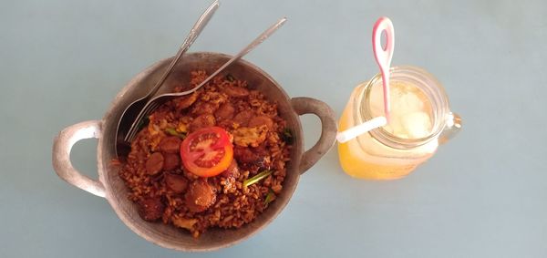 Street food super spicy red fried rice served in a cauldron with iced orange in indonesia