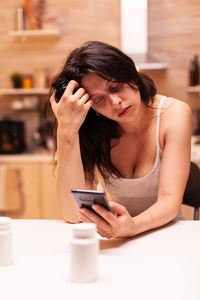 Young woman using mobile phone on table