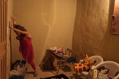 Side view of woman standing on table at home