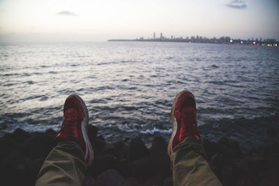 Low section of man on beach against sky