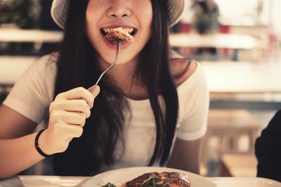 Midsection of woman eating food at table