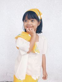 Close-up of smiling girl standing against wall