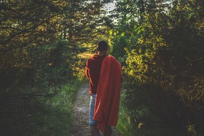 Rear view of young man walking in forest