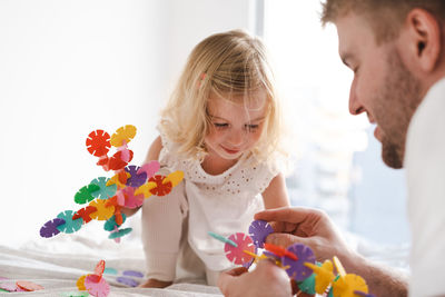 Side view of father and daughter playing with construction 