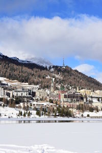 Low angle view of mountain by frozen lake against cloudy sky