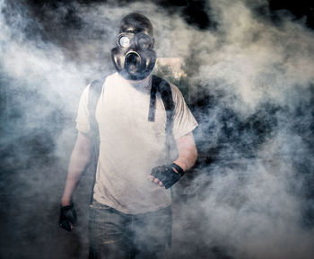 Man wearing gas mask standing under bridge