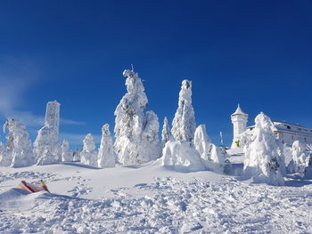 Panoramic view of snow covered landscape against blue sky