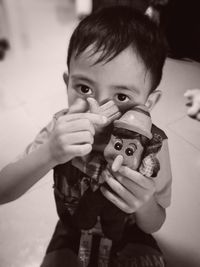 Portrait of boy holding toy at home