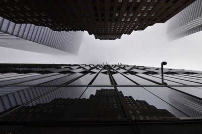 Low angle view of modern buildings against foggy weather