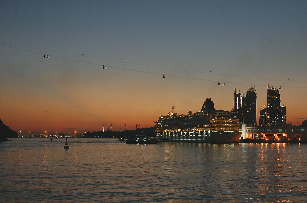 water, sunset, bird, silhouette, built structure, architecture, waterfront, building exterior, flying, sky, sea, river, dusk, animal themes, copy space, harbor, animals in the wild, clear sky, nature, reflection